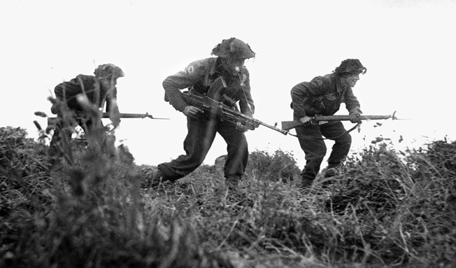An infantry patrol from the British 8th Rifle Brigade, armed with Lee-Enfield rifles and a Bren gun, advances near Eterville, southwest of Caen, on June 29, 1944.